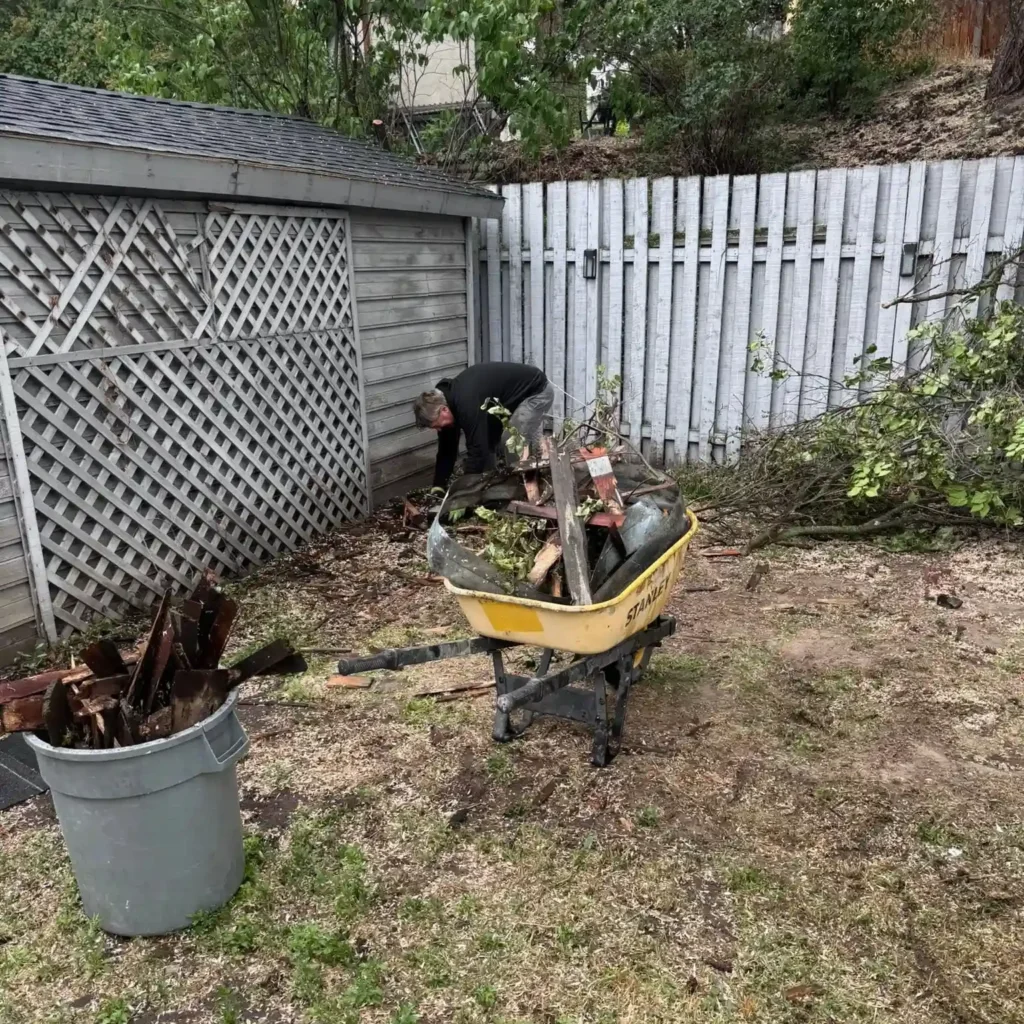 Storm debris cleanup with branches and yard waste being removed from a Kamloops property