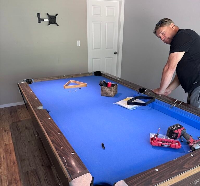 Man disassembling a pool table for removal during a basement cleanout in Kamloops